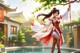 A woman in a red and white dress standing next to a pool.