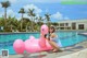 A woman sitting on an inflatable flamingo in a swimming pool.