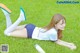 A woman laying on the grass with a bottle of sunscreen.