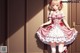 A girl in a pink and white dress standing in front of a door.